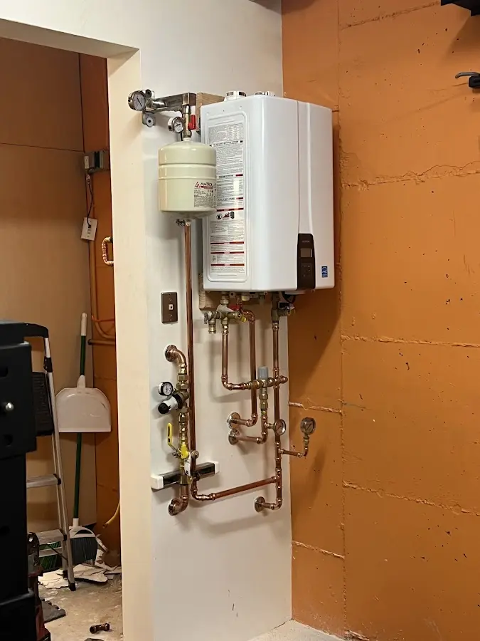 Plumbing technician inspecting water heater connections in Proctor